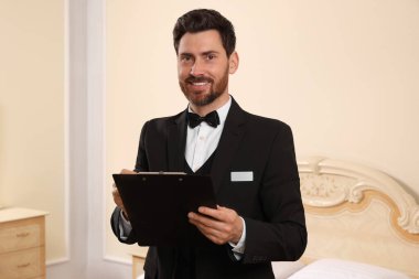 Man in suit with clipboard indoors. Professional butler courses clipart
