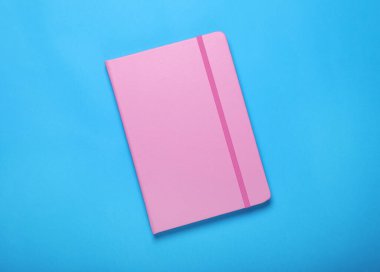 Açık mavi arkaplanda pembe defter, üst görünümde