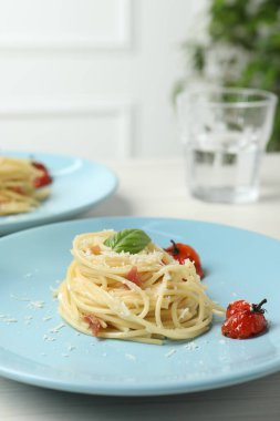 Beyaz ahşap masada servis edilen domatesli ve peynirli lezzetli spagetti, yakın plan. Makarna yemeğinin enfes sunumu