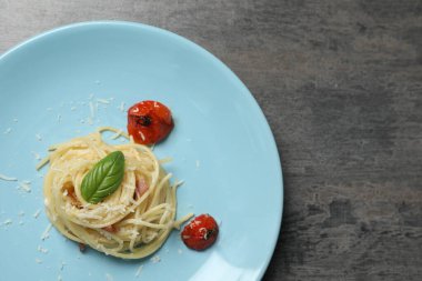 Gri masadaki domatesli ve peynirli leziz spagetti, üst manzara ve yazı için yer. Makarna yemeğinin enfes sunumu