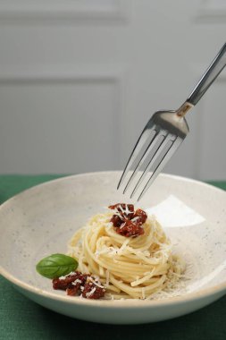 Masadaki tabaktan güneşte kurutulmuş domatesli ve peynirli spagetti yemek, yakından. Makarna yemeğinin enfes sunumu