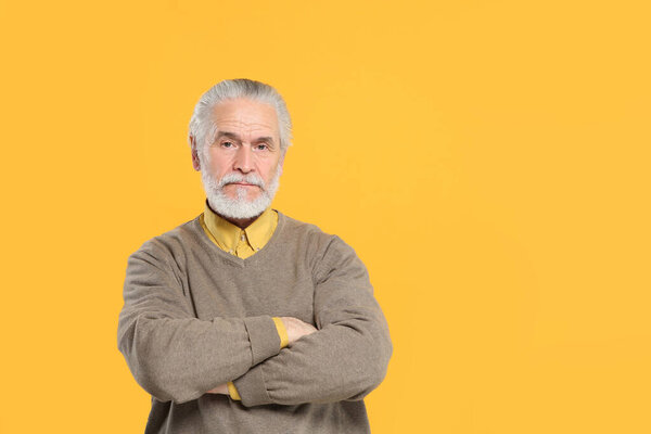 Portrait of handsome senior man on orange background. Space for text