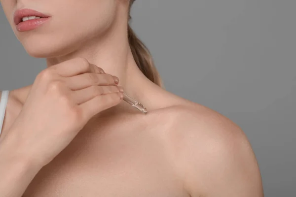 灰色の背景に鎖骨にエッセンシャルオイルを適用する女性 クローズアップ テキストのスペース — ストック写真