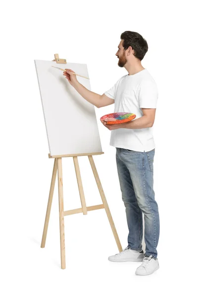白を背景に筆で絵を描く男 キャンバスを保持するためにイーゼルを使用 — ストック写真