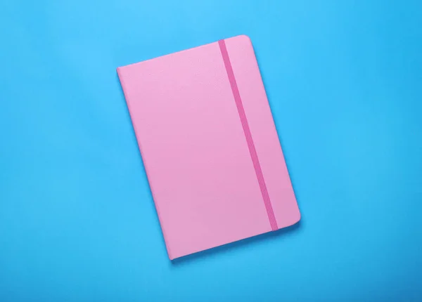 浅蓝色背景的粉红笔记本 顶部视图 — 图库照片
