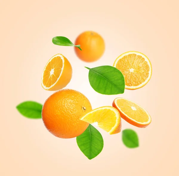 Вирізати Цілі Апельсини Зеленим Листям Літають Бежевому Фоні — стокове фото