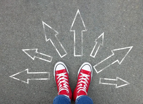 stock image Choosing future profession. Girl standing in front of drawn signs on asphalt, top view. Arrows pointing in different directions as diversity of opportunities