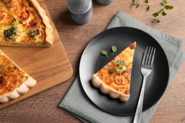 Lezzetli ev yapımı sebzeli kiş, kekik ve çatal ahşap masa, düz uzanmış.