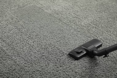 Modern elektrikli süpürgeyle gri halıyı süpürüyor. Metin için boşluk