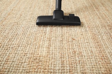 Bej halıyı modern elektrik süpürgesiyle süpürüyor. Metin için boşluk