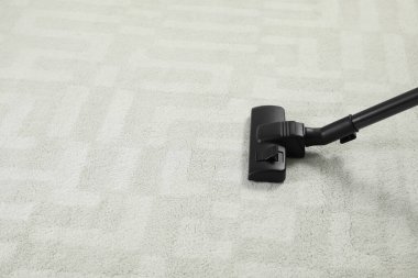 Modern elektrikli süpürgeyle beyaz halı süpürüyorsun. Metin için boşluk