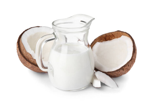 Glass jug of delicious vegan milk and coconuts on white background