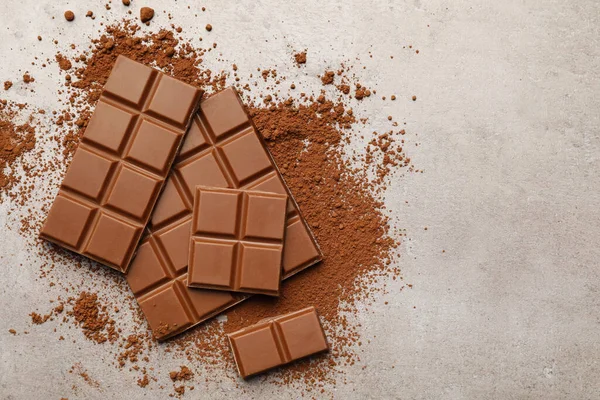 stock image Delicious milk chocolate and cocoa powder on light grey table, flat lay. Space for text