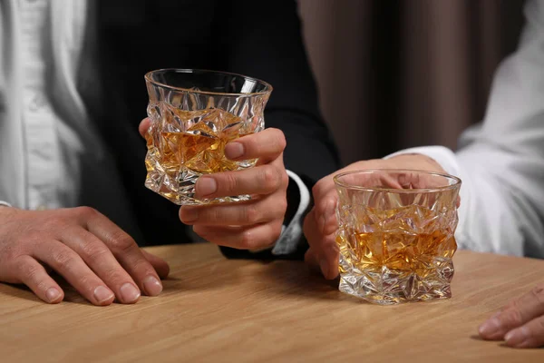 木製のテーブルの中にウイスキーのグラスを持つ男性 クローズアップ — ストック写真