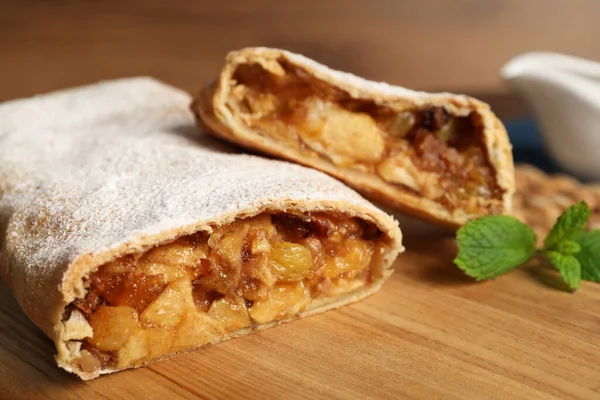 Delicious strudel with apples, nuts and raisins on wooden board, closeup