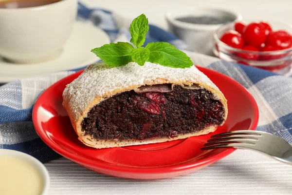 Delicious strudel with cherries and poppy seeds on white wooden table, closeup
