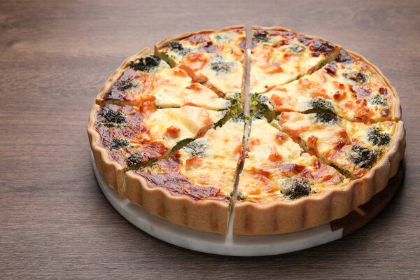 Delicious homemade quiche with salmon and broccoli on wooden table