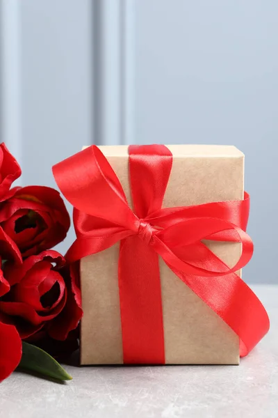 Piękne Pudełko Kokardą Czerwonymi Kwiatami Tulipanów Jasnym Stole Zbliżenie — Zdjęcie stockowe
