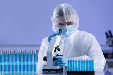 Laboratuvarda mikroskop ve test tüpleriyle çalışan bilim adamları.
