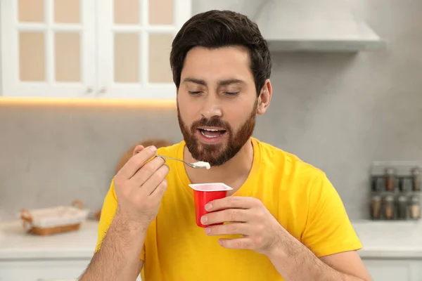 一个英俊的男人在厨房里吃美味的酸奶 — 图库照片