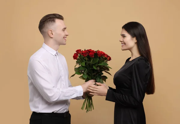 Namorado Apresentando Belas Rosas Bouquet Para Sua Namorada Fundo Bege — Fotografia de Stock