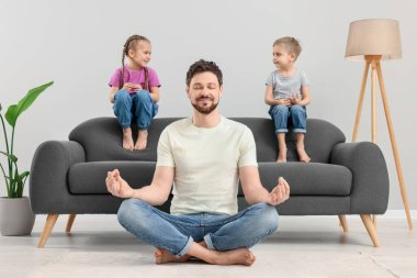 Babası çocukları evdeki kanepede otururken meditasyon yapıyor.