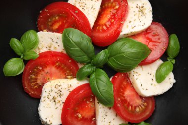 Domatesli Caprese salatası, mozzarella, fesleğen ve baharatlar kasede.