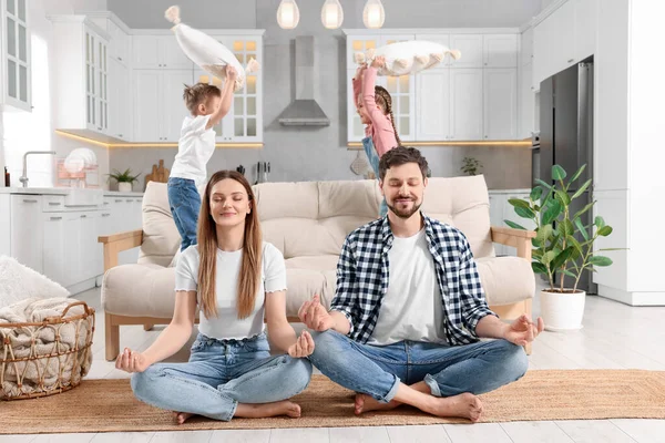stock image Parents meditating while their children playing with cushions at home