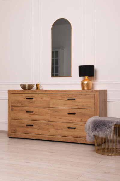 Stylish room interior with chest of drawers, mirror and decor elements
