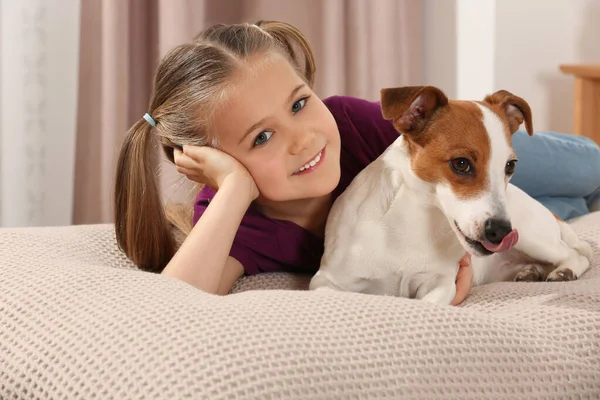 Cute girl with her dog on bed indoors. Adorable pet