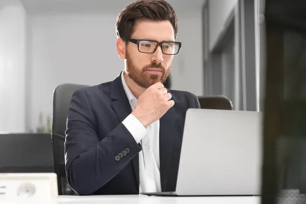 オフィスのホワイトデスクでノートパソコンで働く男 — ストック写真