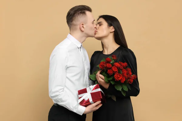 Härligt Par Med Presentask Och Bukett Röda Rosor Kyssas Beige — Stockfoto