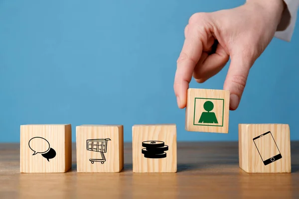 Professional buyer. Man putting wooden cube with green human icon into row with other cubes, closeup