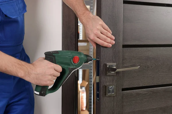 ドアロックを屋内で修理ネジ銃と一致する労働者 クローズアップ — ストック写真