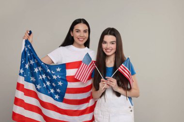 4 Temmuz - ABD 'nin Bağımsızlık Günü. Açık gri arka planda Amerikan bayrakları olan mutlu kadın ve kızı