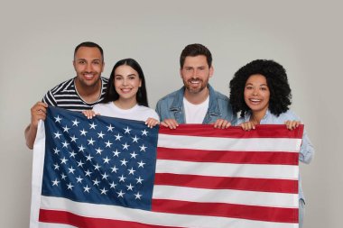 4 Temmuz - ABD 'nin Bağımsızlık Günü. Gri arka planda Amerikan bayrağı taşıyan mutlu arkadaşlar