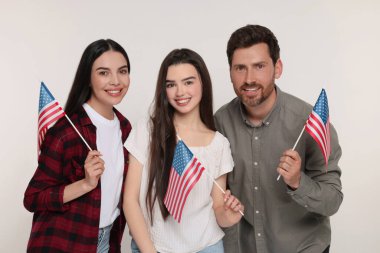 4 Temmuz - ABD 'nin Bağımsızlık Günü. Beyaz arka planda Amerikan bayrakları olan mutlu bir aile.
