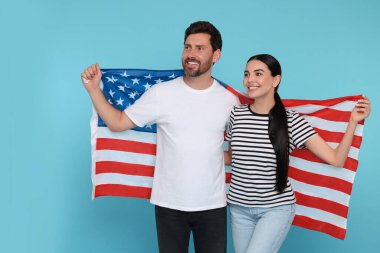 4 Temmuz - ABD 'nin Bağımsızlık Günü. Açık mavi arka planda Amerikan bayrağı taşıyan mutlu bir çift. Metin için boşluk