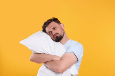 Sarı arka planda yastığı olan mutsuz bir adam. Uykusuzluk sorunu