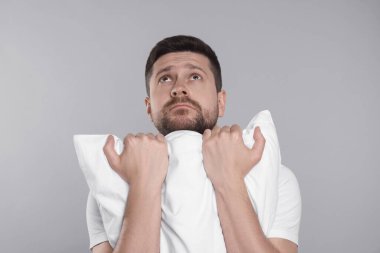 Gri arka planda yastığı olan uykulu bir adam. Uykusuzluk sorunu