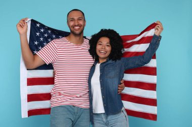 4 Temmuz - ABD 'nin Bağımsızlık Günü. Açık mavi arka planda Amerikan bayrağı taşıyan mutlu çift