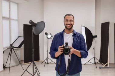 Modern fotoğraf stüdyosunda kamerası olan genç profesyonel fotoğrafçı.