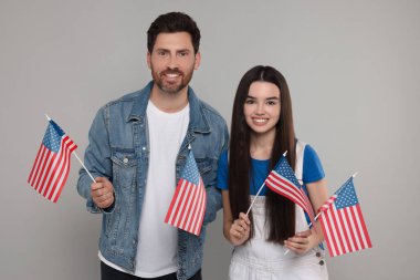4 Temmuz - ABD 'nin Bağımsızlık Günü. Mutlu baba ve kızı açık gri arka planda Amerikan bayraklarıyla