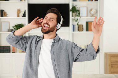 Emotional man dancing while listening music with headphones at home