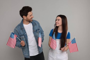 4 Temmuz - ABD 'nin Bağımsızlık Günü. Mutlu baba ve kızı açık gri arka planda Amerikan bayraklarıyla