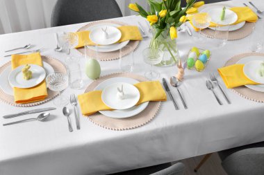 Festive table setting with glasses, painted eggs and vase of tulips. Easter celebration