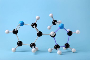 Açık mavi arka planda nikotin molekülü. Kimyasal model
