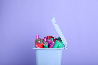 Açık mor arkaplandaki geri dönüşüm kutusunda pek çok kullanılan pil