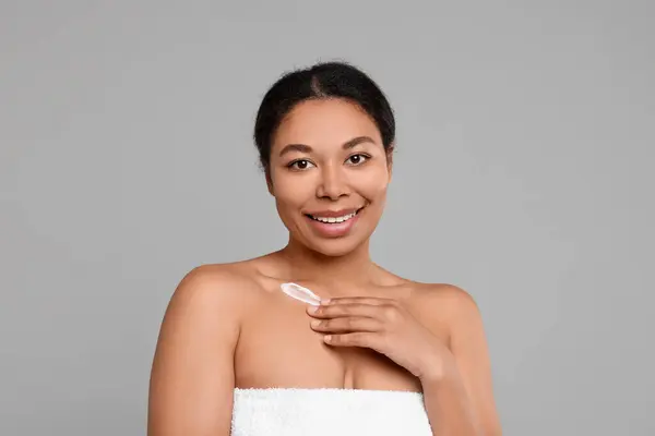 Jonge Vrouw Aanbrengen Crème Lichaam Grijze Achtergrond — Stockfoto