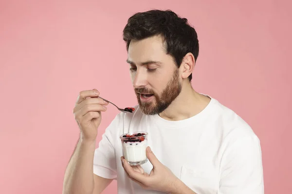 ピンクの背景においしいヨーグルトを食べるハンサムな男 — ストック写真